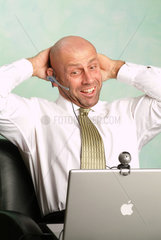 Mann arbeitet an seinem Powerbook und grinst in die Webcam