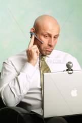 Mann arbeitet an seinem Powerbook und schaut nachdenklich in die Webcam