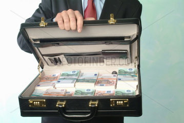 Ein Mann zeigt einen mit Euro-Buendeln gefuellten Koffer