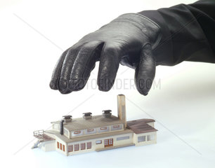 Eine schwarze Hand greift nach einem Fabrikmodell