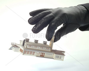 Eine schwarze Hand nimmt Fabrikmodell mit