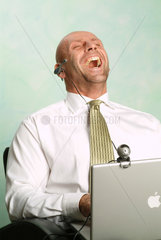 Mann arbeitet an seinem Powerbook und lacht in die Webcam