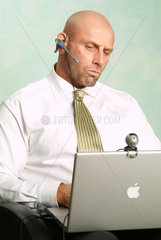 Mann arbeitet an seinem Powerbook und schaut nachdenklich in die Webcam