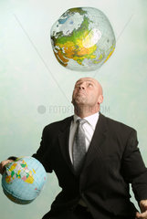 Mann jongliert mit Erdbaellen