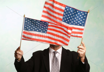 Mann schwenkt amerikanische Flaggen vor dem Gesicht