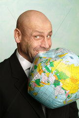 Mann beisst in einen Globus