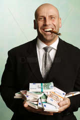 Mann posiert mit Zigarre und Geldbuendeln