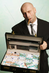 Mann posiert mit Zigarre und Geldkoffer