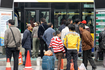 Peking  Fahrgaeste warten an der Bushaltestelle auf den Bus