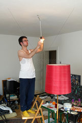 Studenten-WG  Alex montiert eine Lampe