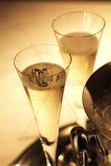 2 Champagnerglaeser stehen neben einem Kuehler auf einem Tablett