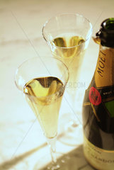 2 Champagnerglaeser stehen neben einer Flasche MOET