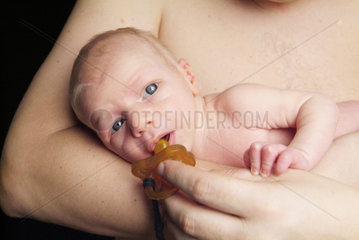 Baby in den Armen seines Vaters  mit Nuckel