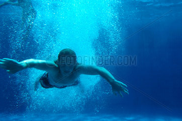 Jugendlicher Turmspringer taucht ins Wasser