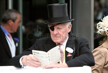 Ascot  Grossbritannien  Mann mit Zylinder und Augenklappe liest im Rennprogramm