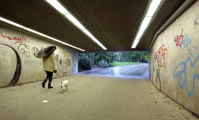 Frau mit Hund und Regenschirm im Fussgaengertunnel  Duesseldorf