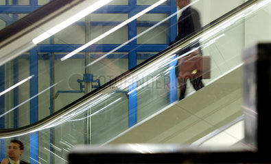 Ein Manager faehrt mit der Rolltreppe abwaerts