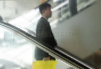 Asiatischer Manager faehrt die Rolltreppe abwaerts  Koeln