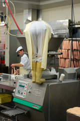 Wurstproduktion  ein Fleischer saeubert den Behaelter der Wurstmaschine