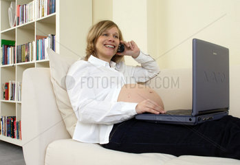 Schwangere  attraktive  moderne  junge Frau mit Laptop
