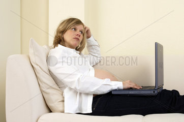 Schwangere  attraktive  moderne  junge Frau mit Laptop