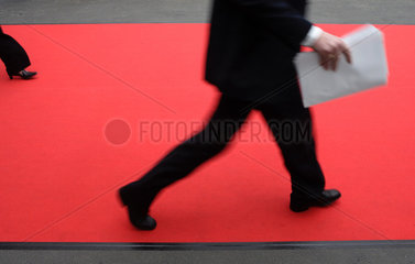 Ein Geschaeftsmann laeuft ueber einen roten Teppich