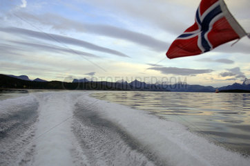 Eine norwegische Flagge weht am Heck eines Motorbootes (Norwegen)