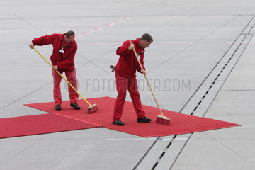 Maenner kehren den roten Teppich fuer Papst Benedikt XVI.