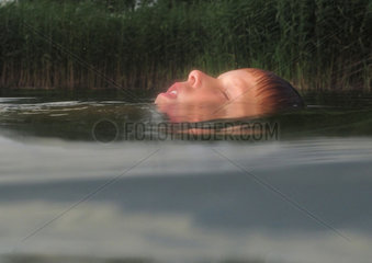 Briescht  Deutschland  Junge schwimmt mit geschlossenen Augen in einem See