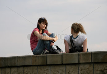 Polen  Krakau  Jugendliche Frauen sitzen auf einer Mauer