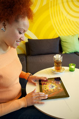 Hamburg  Deutschland  Frau sitzt mit ihrem iPad 2 in einem Cafe und spielt ein Game