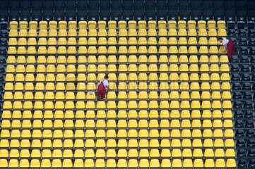 Eine Putzkolonne in rot putzt schwarze und gelbe Sitze