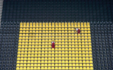 Eine Putzkolonne in rot putzt schwarze und gelbe Sitze