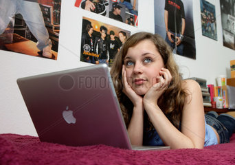 Teenager mit Laptop im Maedchenzimmer