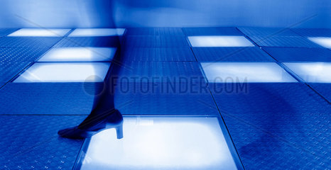 Eine Frau geht durch einen blau illuminierten Gang