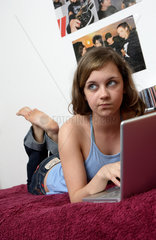 Teenager mit Laptop im Maedchenzimmer