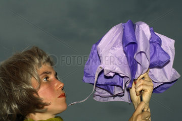 Berlin  Frau oeffnet einen Regenschirm vor dunklem Himmel