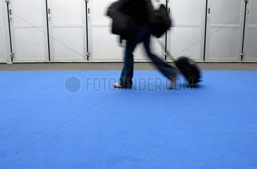 Business  Frau mit Reisegepaeck geht ueber einen blauen Teppich