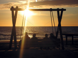 Holland  Bergen aan Zee  Touristen sitzen am Strand beim Sonnenuntergang