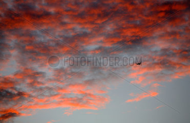 Flugzeug vor roten Wolken beim Sonnenuntergang