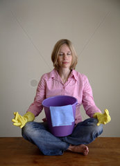 Hausfrau mit Putzeimer entspannt beim Yoga