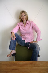 Frau sitzt auf einer Stuhllehne
