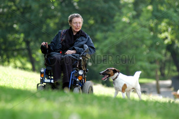 Rollstuhlfahrerin mit Hund im Park  Berlin
