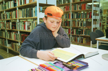 Junge liest in einer Buecherei  Berlin