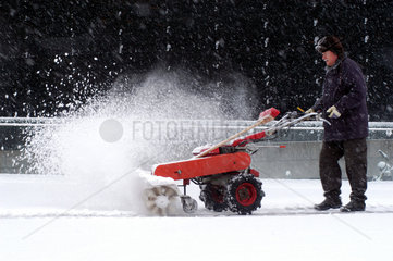 Mann raeumt Schnee mit Maschine  Berlin