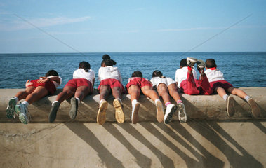Kinder auf einer Mauer der Seepromenade von Havanna