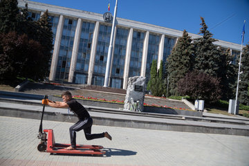 Republik Moldau  Chisinau - Sitz der Regierung der Republik Moldau  vorne ein junger Arbeiter faehrt mit einem Hebegraet fuer Paletten