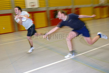 Junge Maenner spielen Frisbee in Sporthalle  Berlin