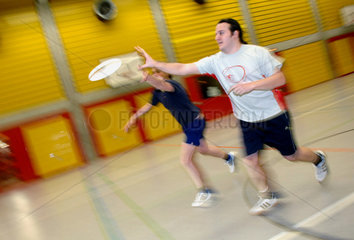 Junge Maenner spielen Frisbee in Sporthalle  Berlin