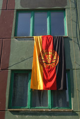 Eine DDR Fahne haengt aus einem Fenster